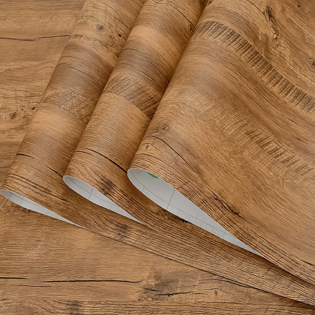 Roll of self-adhesive wood grain wallpaper showing natural brown wood texture and vertical grain lines.