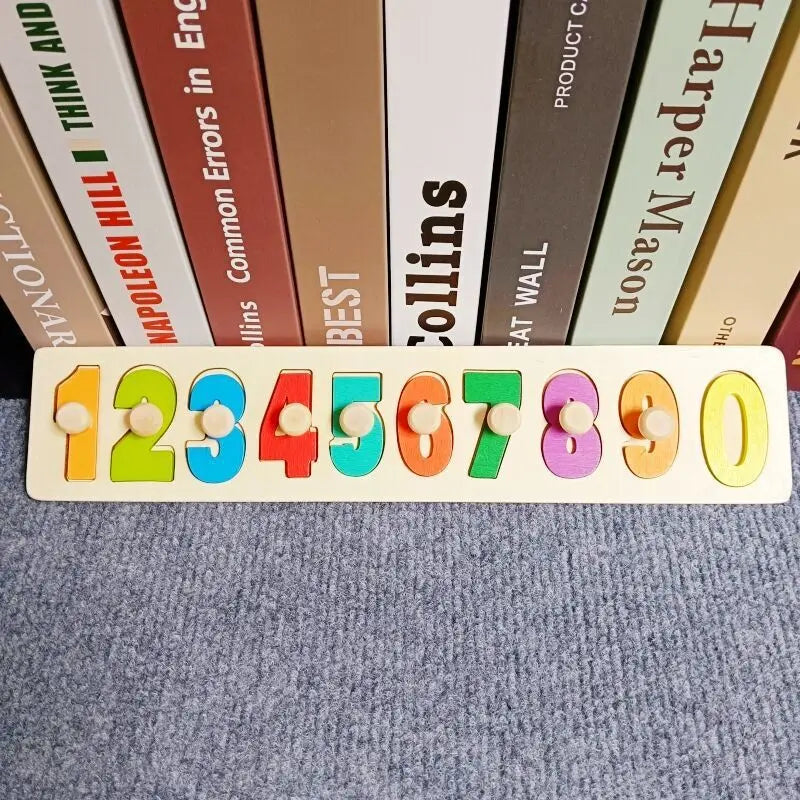 Une rangée de blocs de construction en bois colorés Montessori numérotés de 1 à 0, posés sur une surface de tissu gris.
