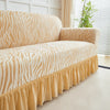 A tan zebra print sofa cover featuring an elastic ruffle skirt on a light-colored sofa.