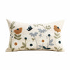 A cream-colored throw pillow cover featuring a delicate floral embroidery design in muted greens, blues, and browns.