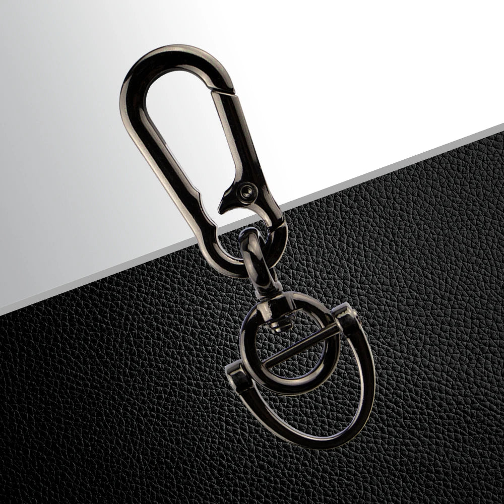 A silver metal key ring with a clasp and a circular loop is displayed on a black leather surface.