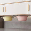 A stainless steel sponge holder with two bowls, one yellow and one pink, mounted under a kitchen cabinet.