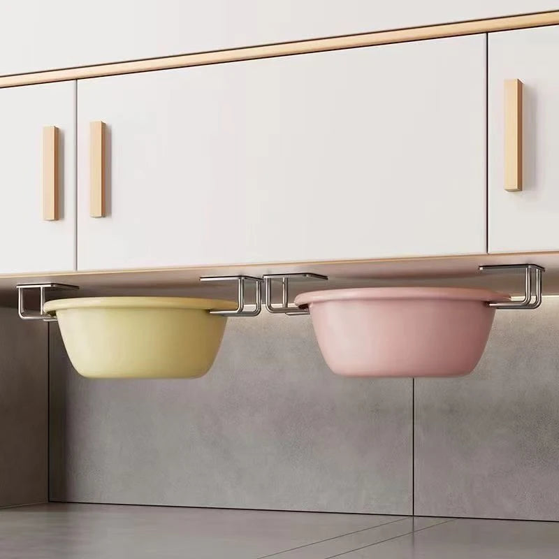 A stainless steel sponge holder with two bowls, one yellow and one pink, mounted under a kitchen cabinet.