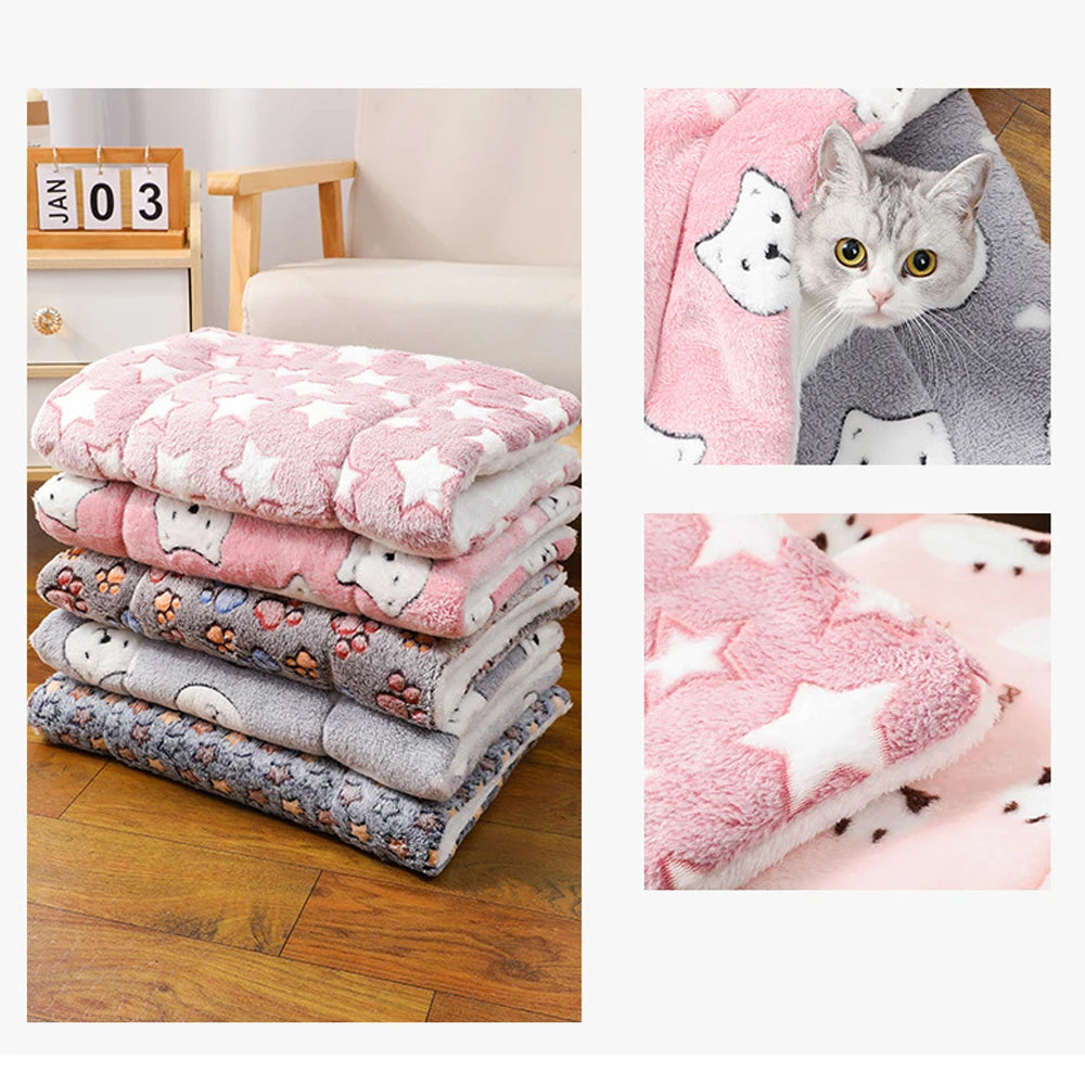 Pink and gray plush sleeping mats for pets, including a cat, stacked on a wooden floor.
