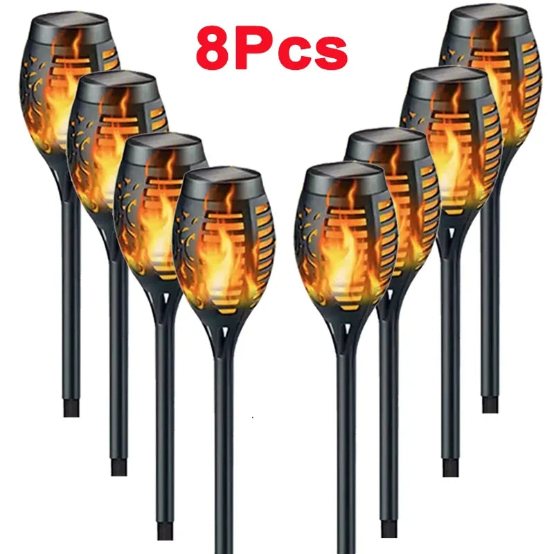 Eight pieces of solar flame torch lights with glowing orange flames on black handles