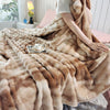 A fluffy brown gradient bubble fleece throw blanket draped over a bed with a cup of tea.