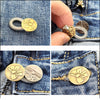 Close-up of brass extender buttons attached to denim fabric, showing the size and texture.