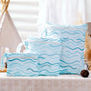 A set of light blue reusable waterproof wet bags with a wavy pattern displayed on a table.