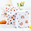 A pair of white waterproof wet dry bags decorated with colorful polka dots and rainbow designs