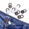 Several adjustable metal extender buttons are displayed on a piece of blue denim jeans.