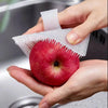 Une main tient une pomme rouge sous un kit de brosse et de gratte silicone blanc.