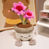 A pink artificial flower plush doll with green stems and a brown pot sits on a white surface.