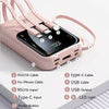 A pink portable power bank with multiple cables and ports is shown on a white surface.