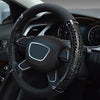 A close-up view of a black car steering wheel with crocodile grain leather covers.