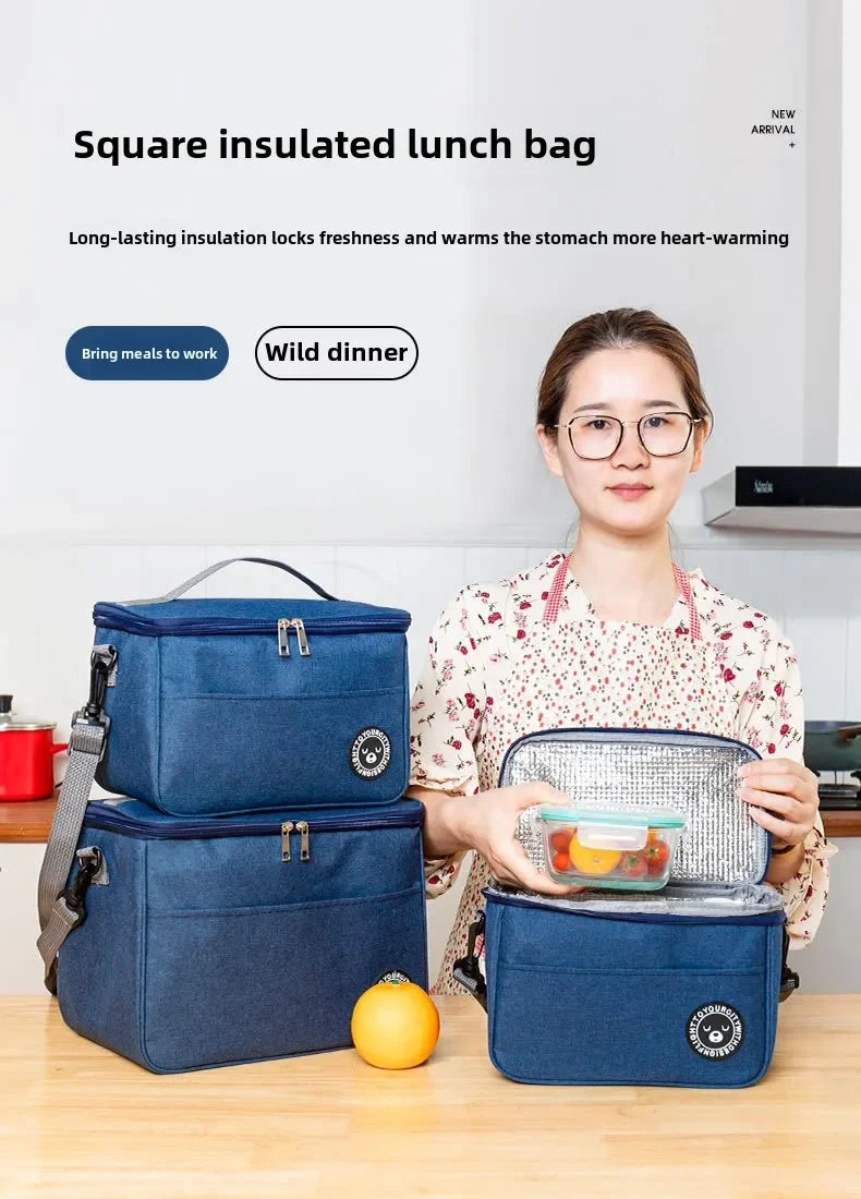 A woman holds a blue insulated lunch bag and an orange fruit on a wooden table.