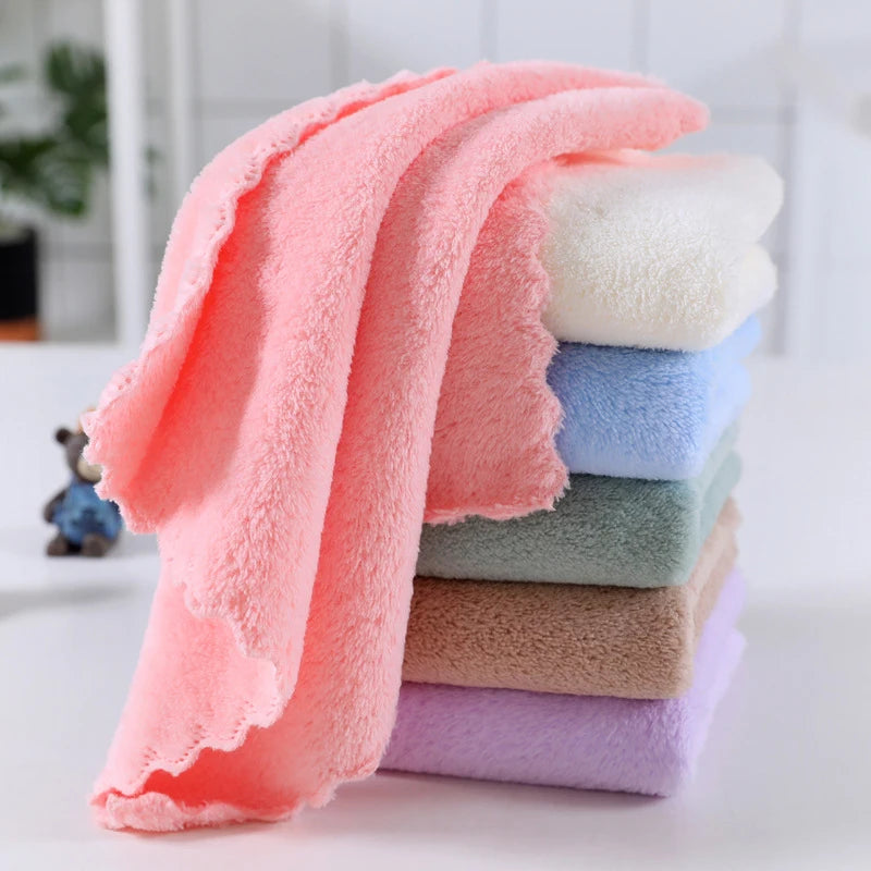 A stack of ten ultra-soft coral velvet face towels in various pastel shades, including pink, blue, and beige.