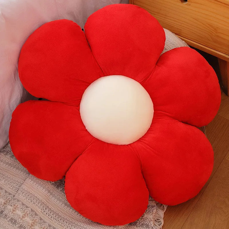 A bright red lifelike sunflower plush pillow with soft fabric petals resting on a light-colored surface.