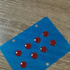Blue glass mouse skates with several red, smooth glide feet resting on a wooden surface.