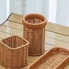 A set of handwoven wicker serving baskets in natural tan color displayed on a wooden surface.