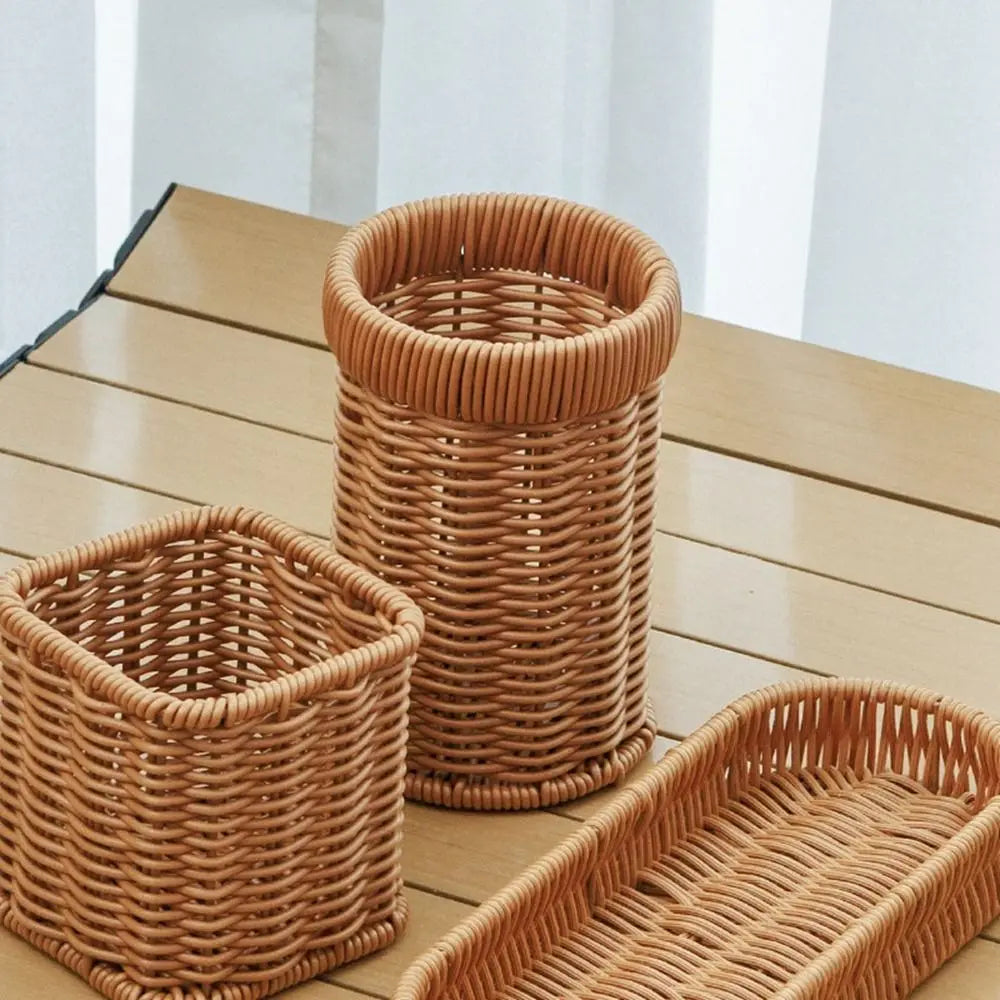 A set of handwoven wicker serving baskets in natural tan color displayed on a wooden surface.