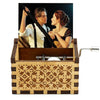 A vintage hand-crank wooden music box with a dark wood casing and a photo of a couple.