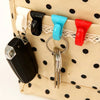 A set of colorful key holder clips attached to a light beige fabric bag with black polka dots.