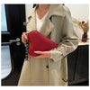A woman holds a red heart-shaped PU coin purse with a strap against a light beige trench coat.