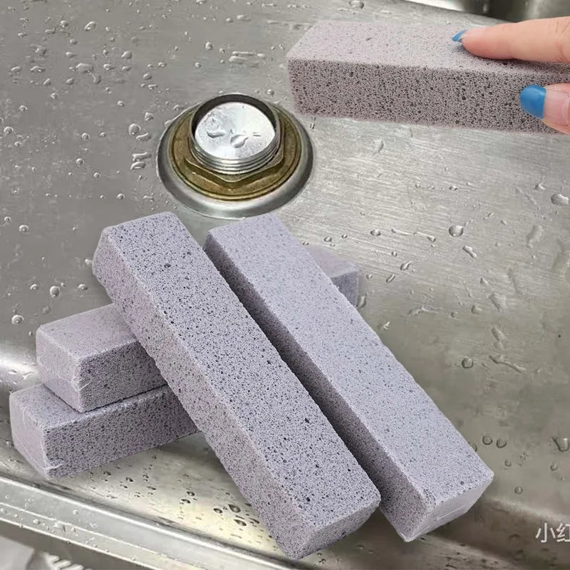 Several gray pumice stone cleaning sticks are displayed on a metal surface with a circular metal object.