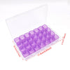 A clear plastic storage case containing numerous small purple diamond painting beads and tools.