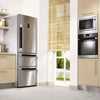 A stainless steel refrigerator with a light beige cabinet and a glass-fronted oven is shown in a kitchen setting.