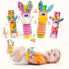 A set of colorful baby rattle socks and teether booties with sensory toys displayed above a sleeping baby.