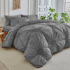 A gray three-dimensional pleated floral duvet cover set displayed on a bed with white trim and greenery.
