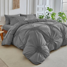 A gray three-dimensional pleated floral duvet cover set displayed on a bed with white trim and greenery.