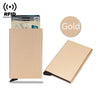 A beige slim metal RFID blocking card holder with a pop-up design next to a stack of cards and a gold circle icon.