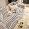 A gray plush sofa cushion cover featuring quilted texture and cream accent pillows on a light-colored sofa.