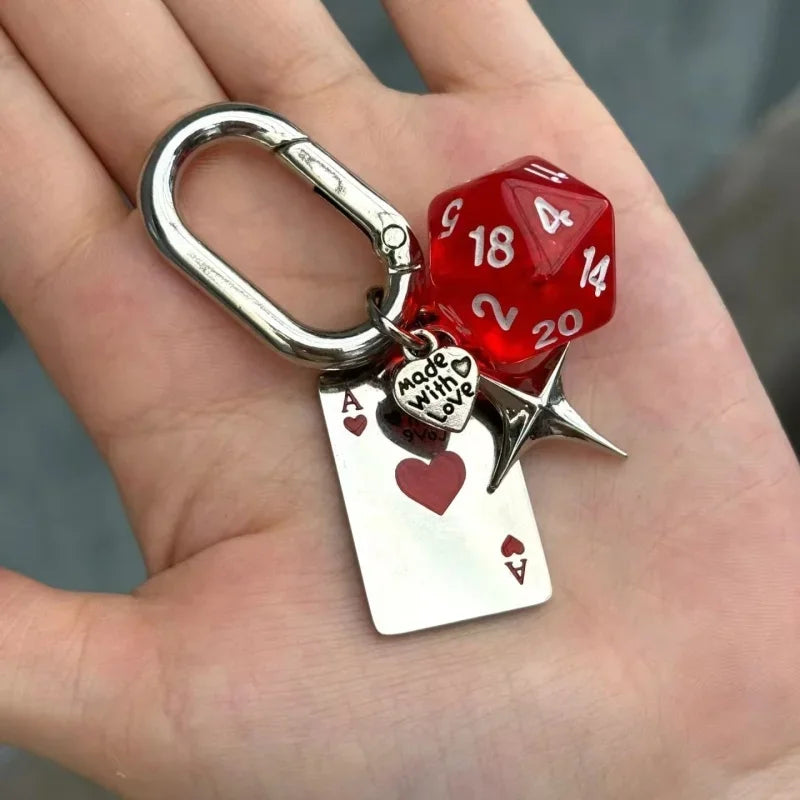A silver keychain charm featuring a red dice and a heart-shaped card, designed with a D-shaped buckle.