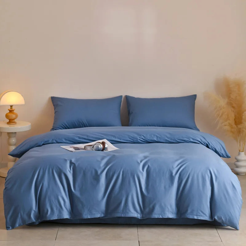A light blue quilted duvet cover set with matching pillowcases displayed on a bed against a white wall.