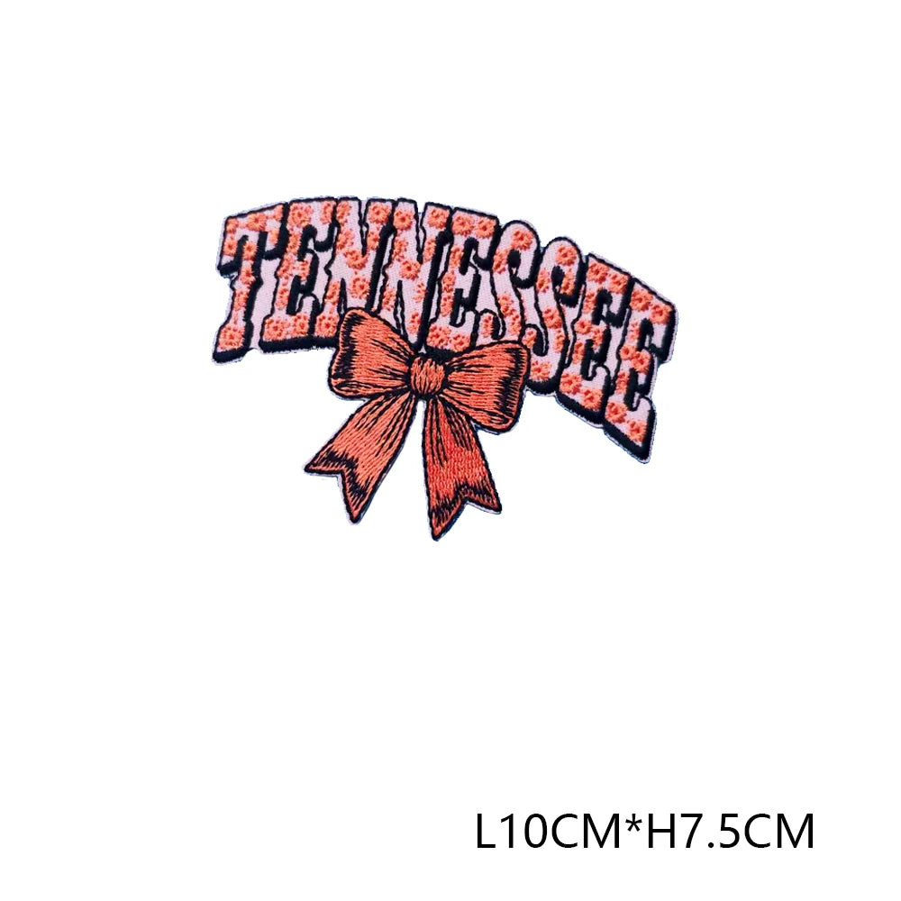 An embroidered letter patch spelling out TENNESSEE with a peach-colored bow.