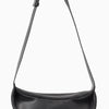 Schwarze, echte Leder-Crossbody-Tasche mit langer Tragegurt gegen weißen Hintergrund.