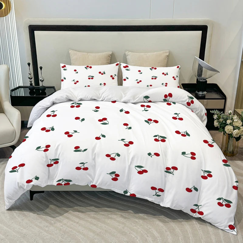 White duvet cover set with a red cherry print featuring multiple pillows on a bed.