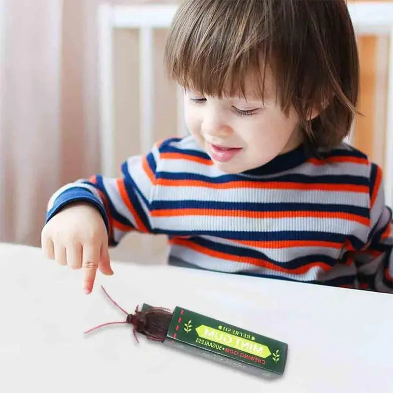 A child is looking at a tube of realistic cockroach prank gum on a white surface.