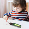 A child is looking at a tube of realistic cockroach prank gum on a white surface.