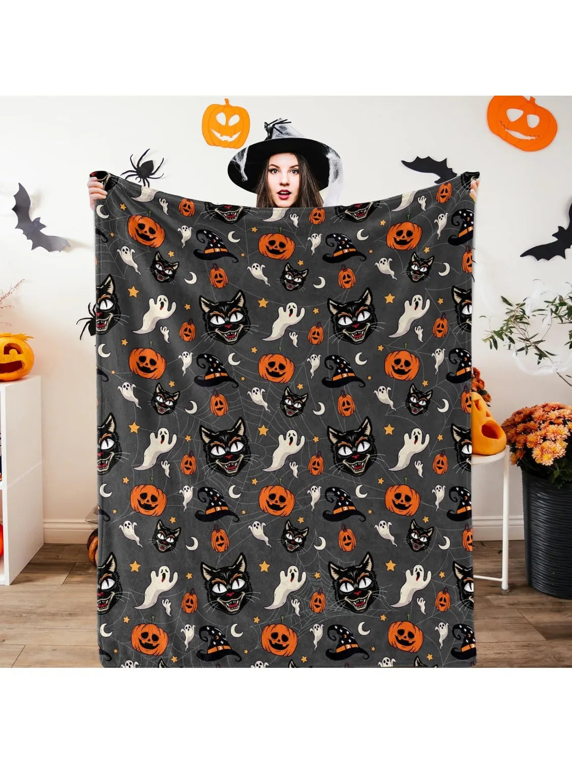 A dark gray flannel throw blanket featuring an all-over spooky Halloween print with bats, cats, and pumpkins.