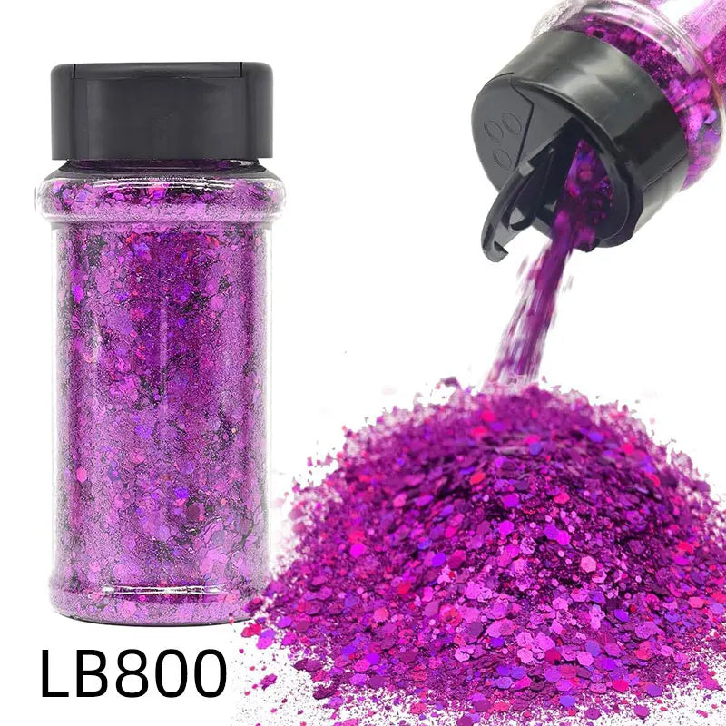 A glass jar of purple holographic nail glitter mix next to a pile of loose magenta glitter.