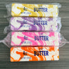 Four different colored salted butter fidget sticks are packaged in clear plastic.