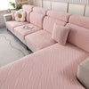 Una funda de asiento y cojín elástico de sofá color rosa y acanalado se muestra en un sofá de color claro en una habitación b