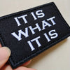 Black embroidered tactical morale patch with white text reading It is what it is