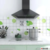 A stainless steel pot sits on a stovetop next to a black kitchen hood and a white tiled splashback.