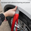 A hand is applying a red carbon fiber wheel arch trim strip with adhesive backing to a car wheel.