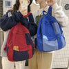 A person is holding a blue canvas patchwork backpack while standing next to another person.